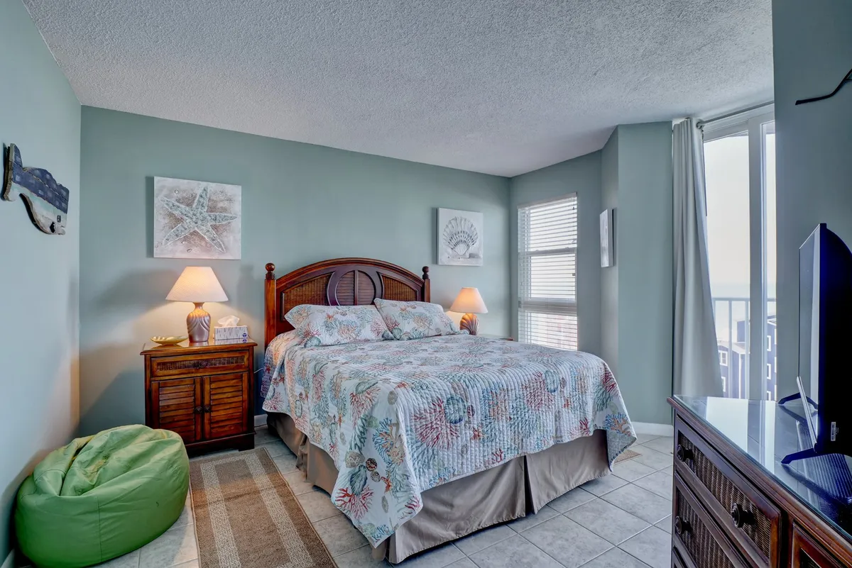 A tranquil bedroom featuring a cozy bed, nightstand, window with beautiful views, and a bean bag chair. The space exudes calm and comfort, inviting guests to unwind, read, or enjoy a cup of coffee while watching TV or gazing out the window.