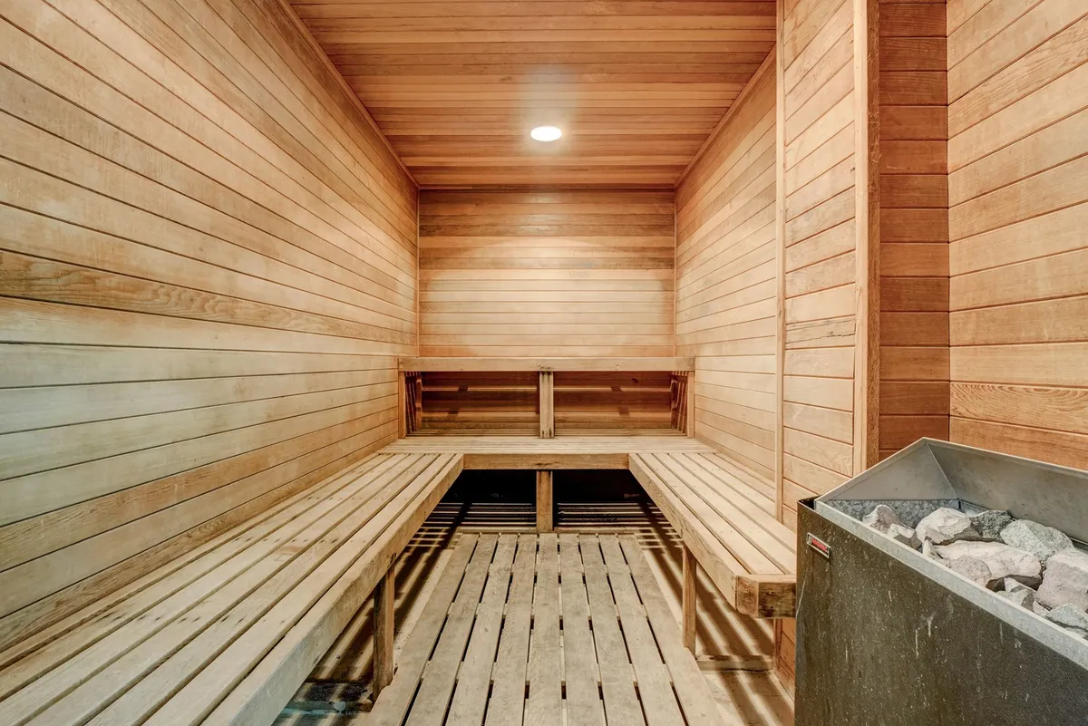 A cozy, wood-paneled sauna room with warm lighting and inviting benches, evoking a sense of relaxation and wellness. The setting is intimate, perfect for couples or friends seeking a tranquil retreat after a day of exploring or socializing.