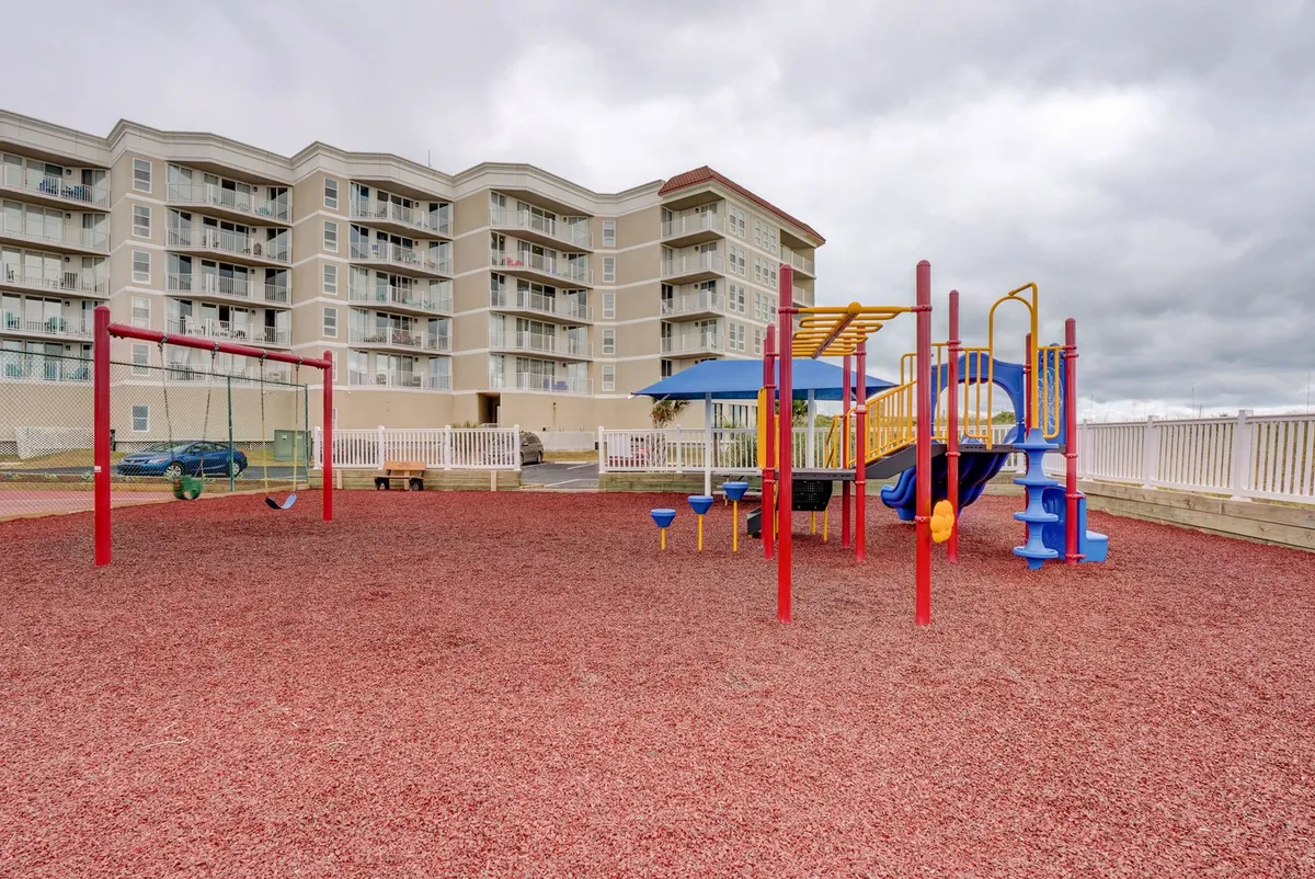 A vibrant, modern playground featuring colorful swings, play structures, and families gathering nearby while children play. The sunny, inviting setting encourages active outdoor recreation and community connection.